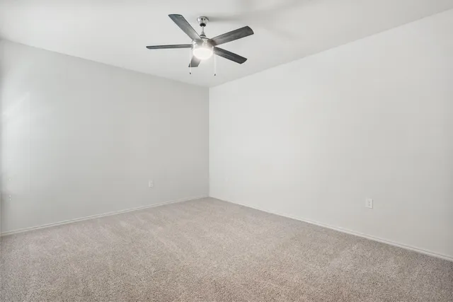an empty room with a ceiling fan and a window