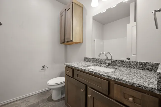 a bathroom with a granite countertop toilet sink and mirror