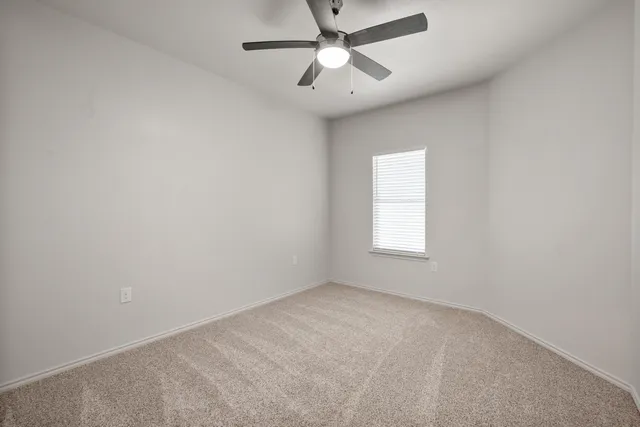 an empty room with a window and a fan