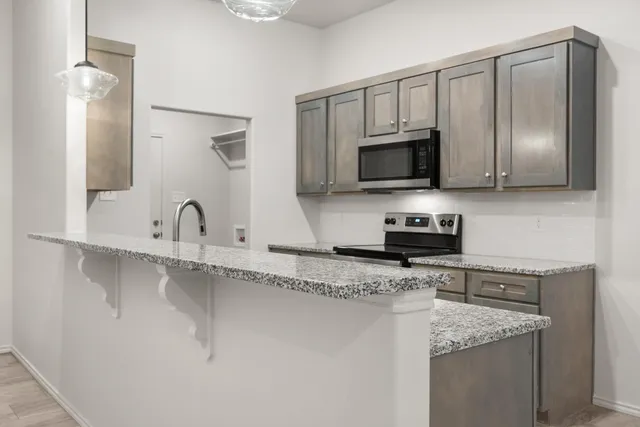 a kitchen with granite countertop a sink and a stove top oven with wooden floor