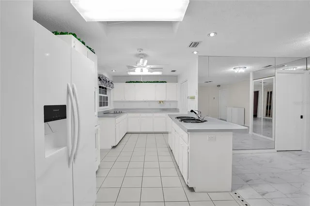 a kitchen with stainless steel appliances kitchen island granite countertop a sink and a refrigerator