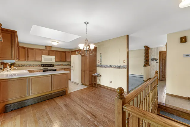 a open kitchen with stainless steel appliances a refrigerator a stove a sink dishwasher and white cabinets with wooden floor