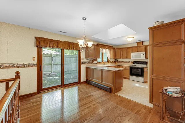 a kitchen with stainless steel appliances granite countertop a refrigerator a oven a sink with island and chairs