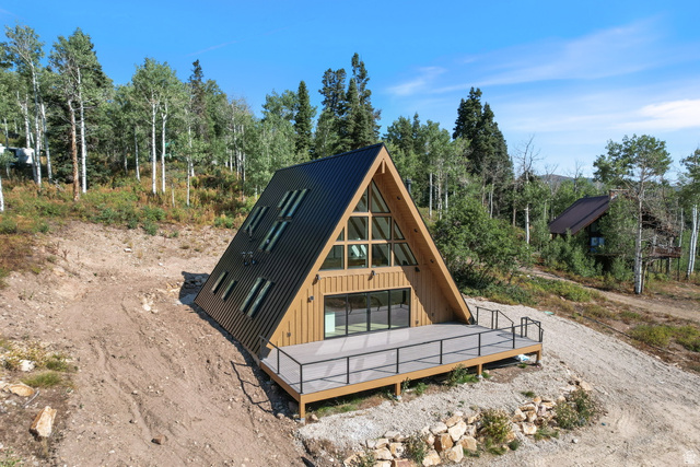 1833 Pine Loop Road Coalville, UT 84017 - Photo 1 of 26 A-frame architectural style with a black metal roof, natural wood siding, and an expansive deck featuring a black metal railing