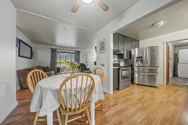 a kitchen with granite countertop a refrigerator a stove a dining table and chairs
