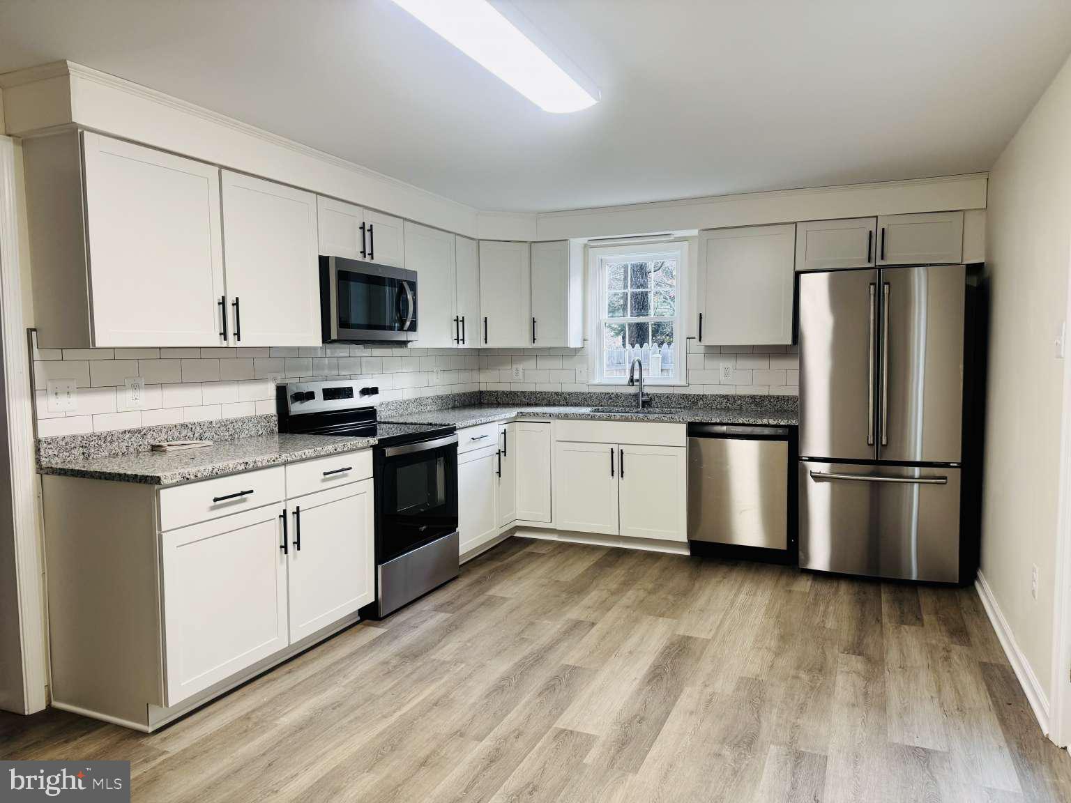 905 Crystal Rock Road Lusby, MD 20657 - Photo 2 of 22 a kitchen with stainless steel appliances granite countertop a stove top oven a refrigerator a sink and dishwasher with wooden floor