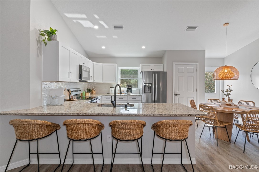 4865 South Tromp Loop Homosassa, FL 34448 - Photo 5 of 30 a kitchen with stainless steel appliances granite countertop a table chairs and a refrigerator