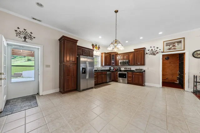 a view of kitchen with stainless steel appliances granite countertop a refrigerator and microwave