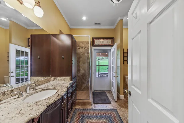 a bathroom with a granite countertop shower a sink and a mirror