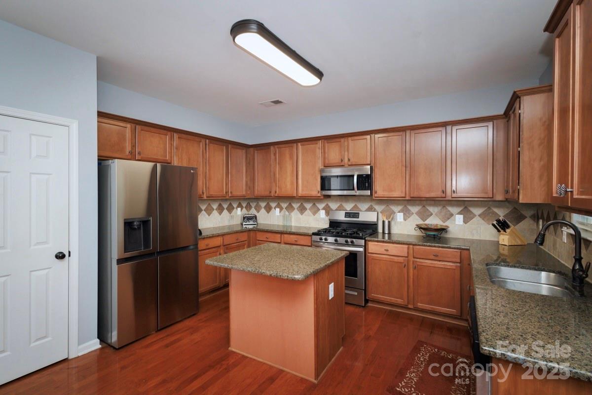 1457 Prestbury Road Northwest Concord, NC 28027 - Photo 5 of 19 a kitchen with granite countertop stainless steel appliances a refrigerator a sink a stove cabinets and wooden floor