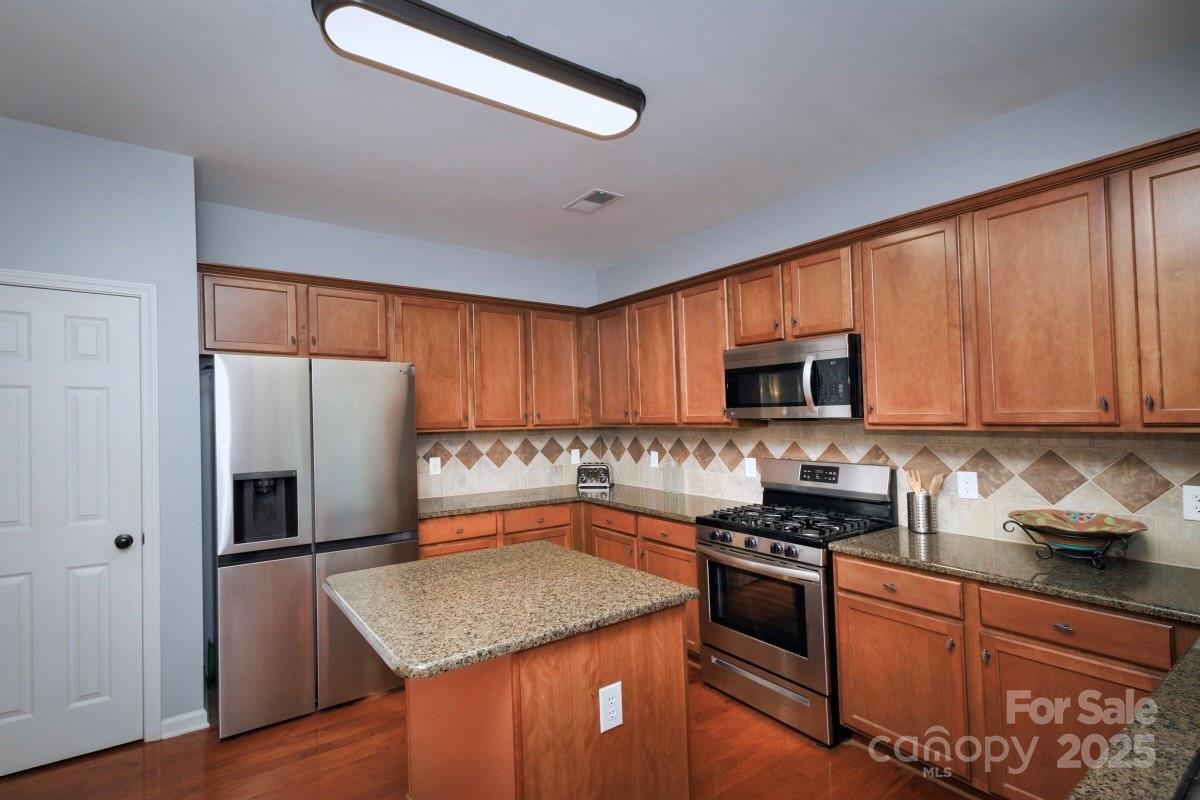 1457 Prestbury Road Northwest Concord, NC 28027 - Photo 6 of 19 a kitchen with stainless steel appliances granite countertop a refrigerator a sink dishwasher a stove and white cabinets with wooden floor