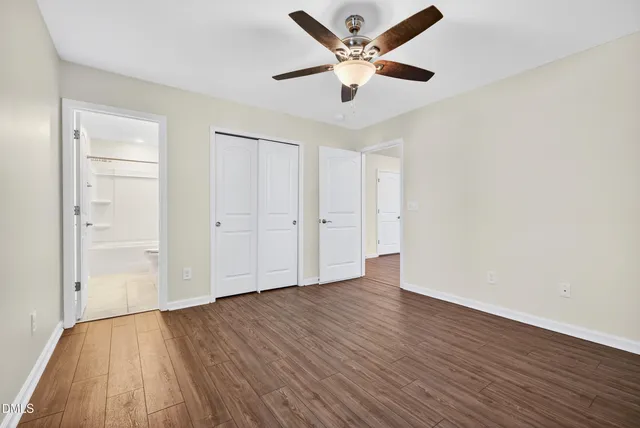 an empty room with wooden floor and a ceiling fan