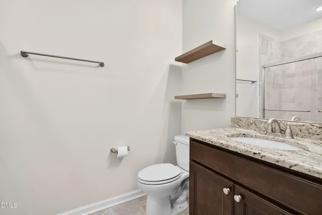 a bathroom with a granite countertop sink mirror vanity and toilet
