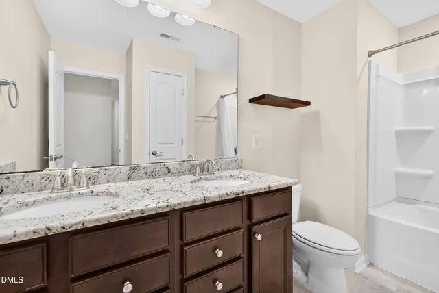a bathroom with a granite countertop sink toilet and mirror