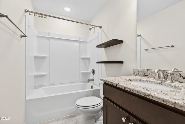 a bathroom with a granite countertop sink a toilet and shower