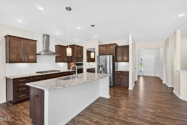 a large kitchen with stainless steel appliances a refrigerator and a stove top oven