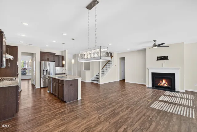 a living room with stainless steel appliances furniture wooden floor and a kitchen view