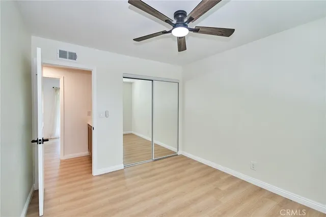 an empty room with wooden floor and a ceiling fan