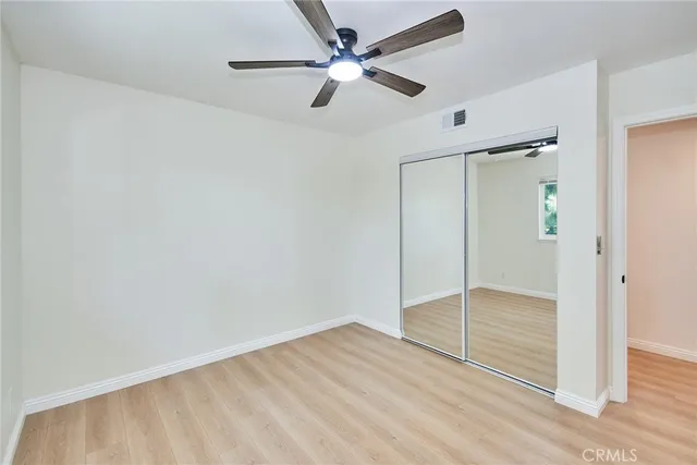 an empty room with closet and a ceiling fan