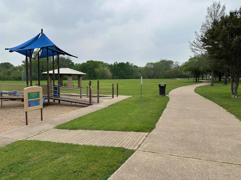 3101 Buckthorn Street Forney, TX 75126 - Photo 35 of 40 Expansive park area featuring a paved walking path, a covered playground structure with a blue canopy, a picnic pavilion, and mature trees bordering the green space