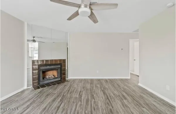 a view of an empty room with wooden floor fireplace and a window
