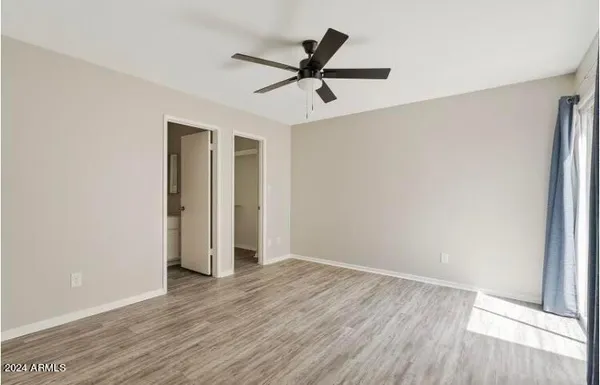 a view of an empty room with wooden floor and a ceiling fan