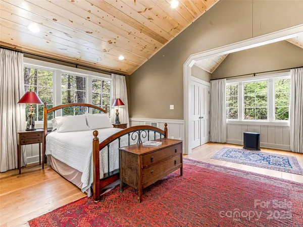 a spacious bedroom with a bed and wooden floor