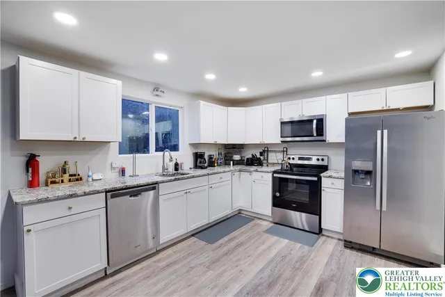 a kitchen with stainless steel appliances granite countertop a refrigerator and a stove top oven