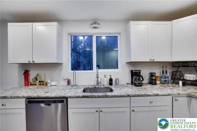 a kitchen with granite countertop white cabinets and sink