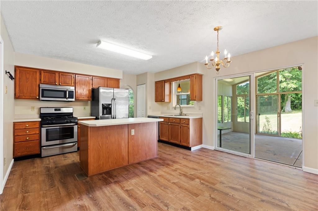 6 Wellington Court McKees Rocks, PA 15136 - Photo 6 of 24 a kitchen with stainless steel appliances kitchen island granite countertop a stove top oven a sink dishwasher a refrigerator and a dining table with wooden floor