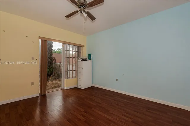 an empty room with wooden floor cabinet and windows
