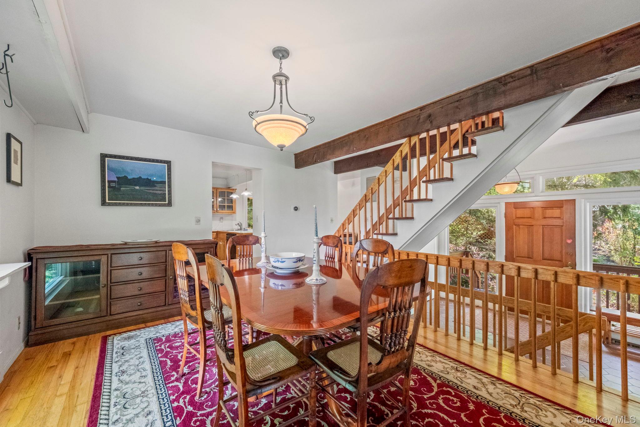 73 Bramblebrook Road Ardsley, NY 10502 - Photo 8 of 35 Dining area featuring hardwood flooring, exposed beam ceiling, a chandelier light fixture, and a wood staircase with wood balusters