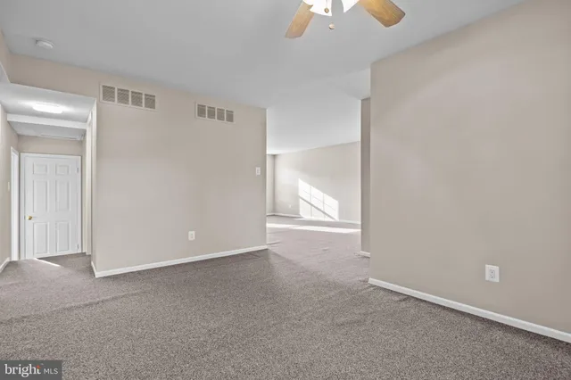 an empty room with windows and chandelier fan