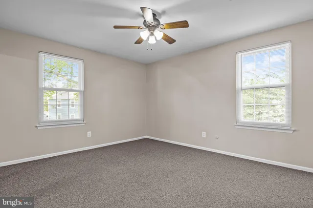 an empty room with a window and a fan