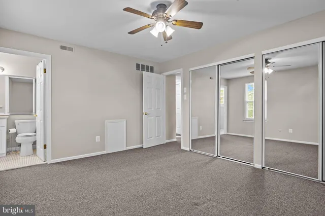 an empty room with closet and a chandelier fan