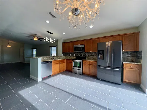 a kitchen with stainless steel appliances granite countertop a refrigerator a stove top oven a sink and dishwasher