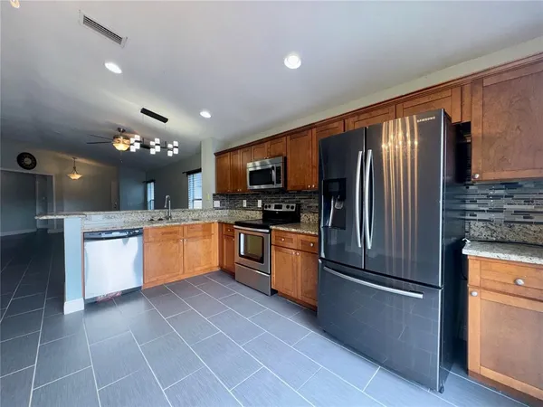 a large kitchen with a large counter top stainless steel appliances and cabinets