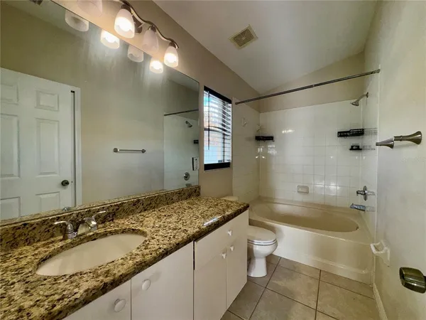 a bathroom with a granite countertop tub sink and mirror
