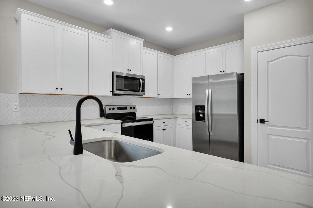 748 Morgans Treasure Road St. Augustine, FL 32084 - Photo 3 of 10 a kitchen with a refrigerator a microwave a sink and cabinets