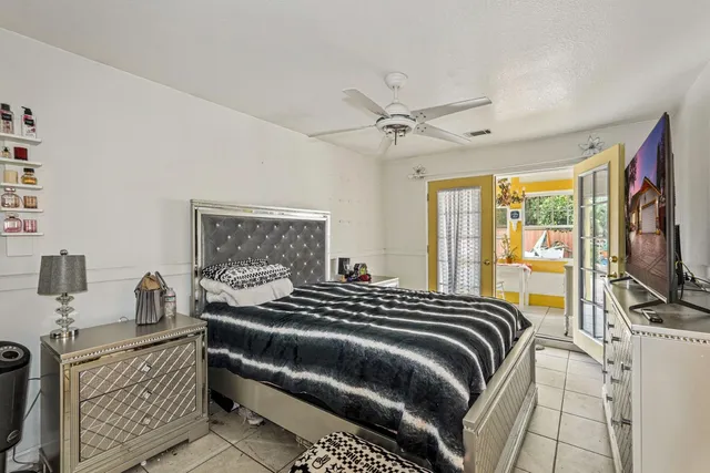 a bedroom with a bed a flat screen tv and a large window