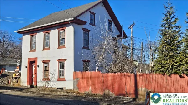 a front view of a house with large trees
