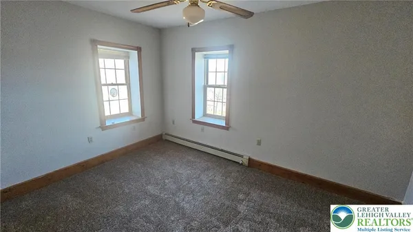 an empty room with windows and fan