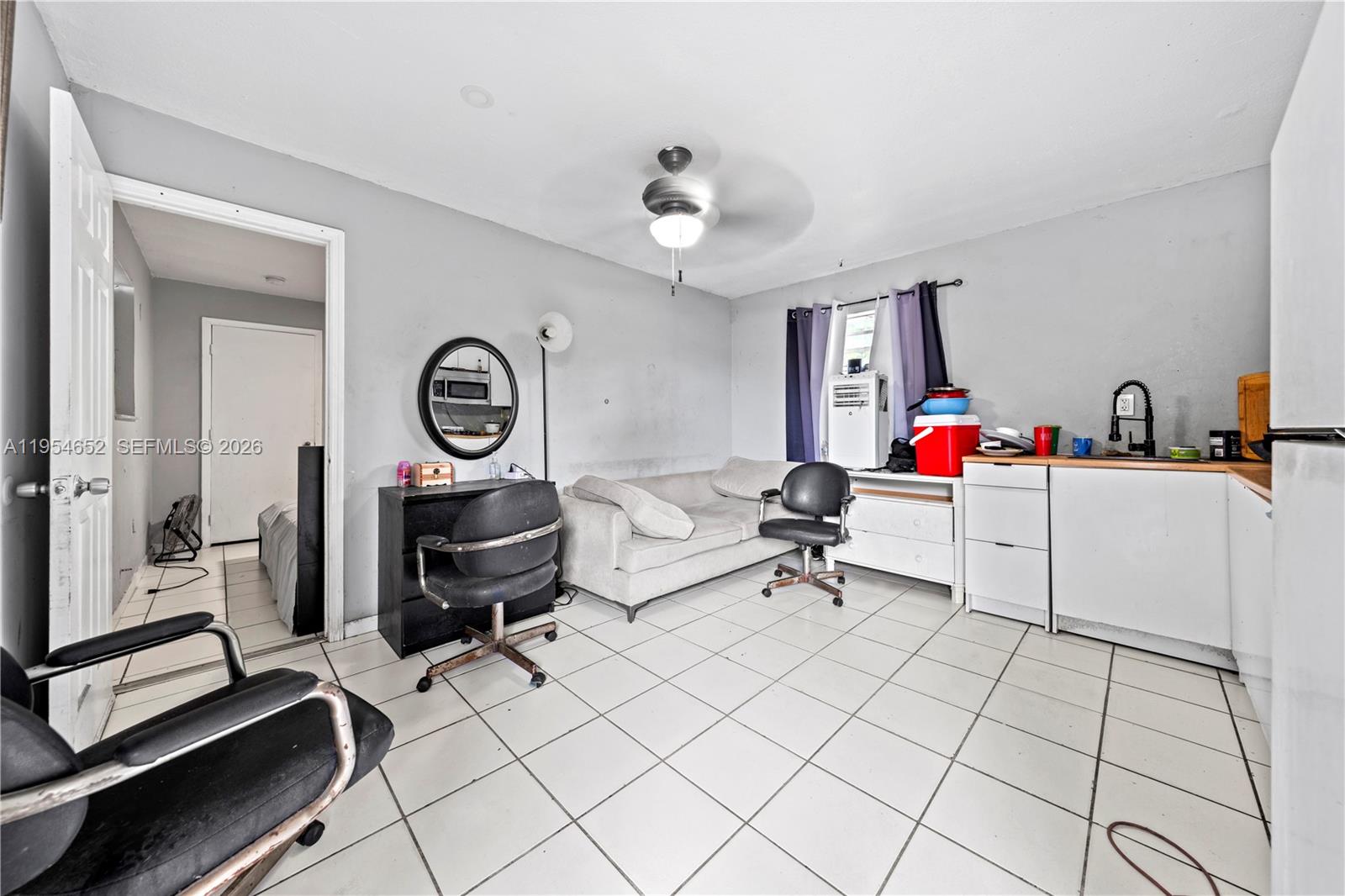 2110 Northwest 34th Street Miami, FL 33142 - Photo 26 of 33 a living room with furniture a clock and a flat screen tv