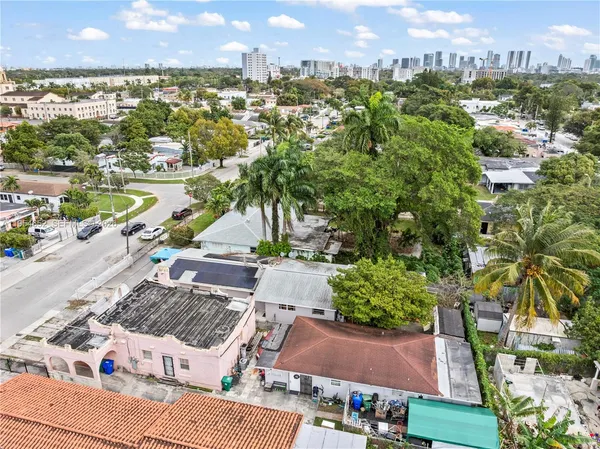 a view of a white house with a large tree and wooden fence