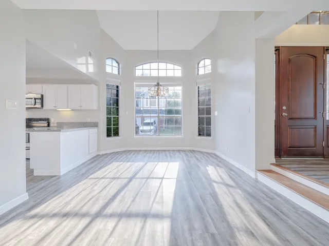 a view of an empty room with kitchen and window
