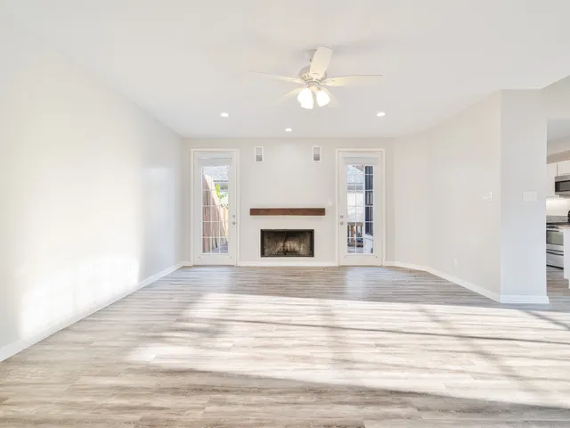 a view of an empty room with wooden floor and fireplace