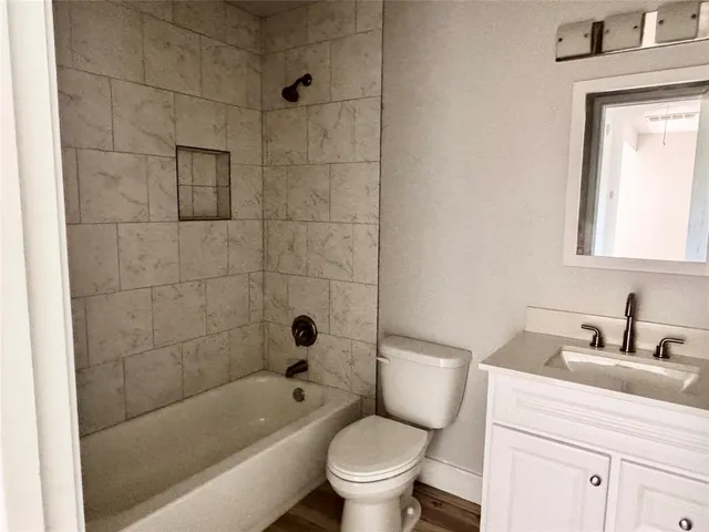 a bathroom with a bathtub shower sink mirror vanity and toilet