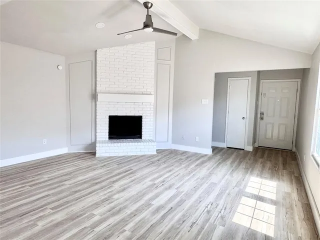 an empty room with wooden floor a fireplace and windows