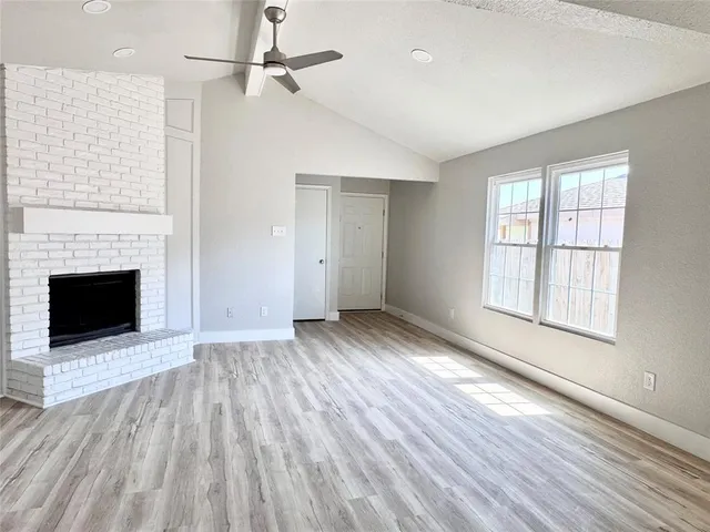 an empty room with windows and a fireplace