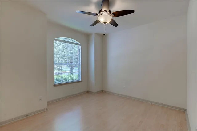 an empty room with a window and a fan